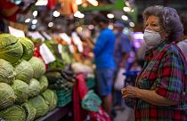 A customer wearing a face mask waits to buy vegetables at the Maravillas market in Madrid.