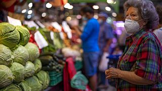 Un cliente con mascarilla espera para comprar verduras en el mercado Maravillas de Madrid.