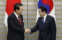 South Korean President Yoon Suk Yeol and Japanese Prime Minister Fumio Kishida shake hands