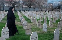 A woman passes by graves in Iraq.
