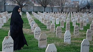 A woman passes by graves in Iraq.