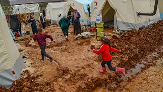 أطفال يركضون في مكان موحل بجوار الخيام التي تبرعت بها المنظمة الإنسانية التركية كيزيلاي، بعد الفيضانات في أديامان، جنوب شرق تركيا في 16 مارس 2023