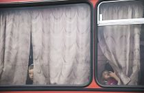 Children look out from a bus before leaving for a train station at a refugee camp set up by the Russian Emergencies Ministry about 10km from the Russia-Ukrainian border.