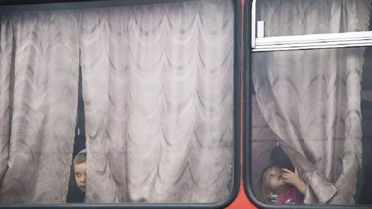 Children look out from a bus before leaving for a train station at a refugee camp set up by the Russian Emergencies Ministry about 10km from the Russia-Ukrainian border.