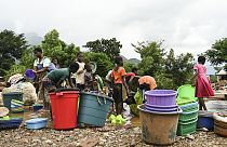 Women and children wash plastic kitchen utensils in a stream in Phalombe, southern Malawi,March 17, 2023.