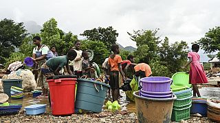Women and children wash plastic kitchen utensils in a stream in Phalombe, southern Malawi,March 17, 2023.