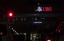 The illuminated logos of the Swiss banks Credit Suisse and UBS are seen on buildings next to traffic lights in Zurich, Switzerland