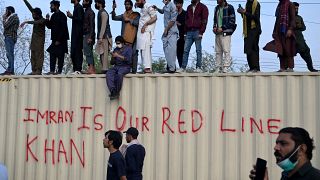 مؤيدو رئيس الوزراء الباكستاني السابق عمران خان يقفون على حاوية كتب عليها "عمران خان خطنا الأحمر" في إسلام أباد