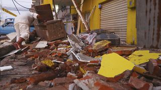 A resident recovers belongings amid the debris of a collapsed home after an earthquake shook Machala, Ecuador, March 18, 2023. 