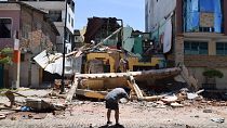 A man takes a photo of a building that collapsed after an earthquake shook Machala, Ecuador, Saturday, March 18, 2023. 