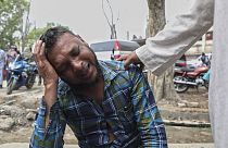 An unidentified man grieves as relatives receive bodies of victims of a road accident