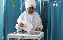 Eine Frau in kasachischer Nationaltracht gibt am Sonntag, den 19. März 2023, in einem Wahllokal in der kasachischen Hauptstadt Astana ihre Stimme ab