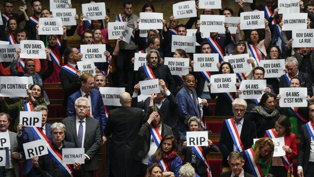 French lawmakers in the National Assembly hold papers reading: "64 years. It is no." 20 March