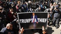 Una mujer sostiene un cartel como parte de una protesta frente al tribunal antes de la acusación anticipada del expresidente Donald Trump, 20 de marzo de 2023, Nueva York