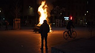 Protester stands in front of a fire in the streets of France.