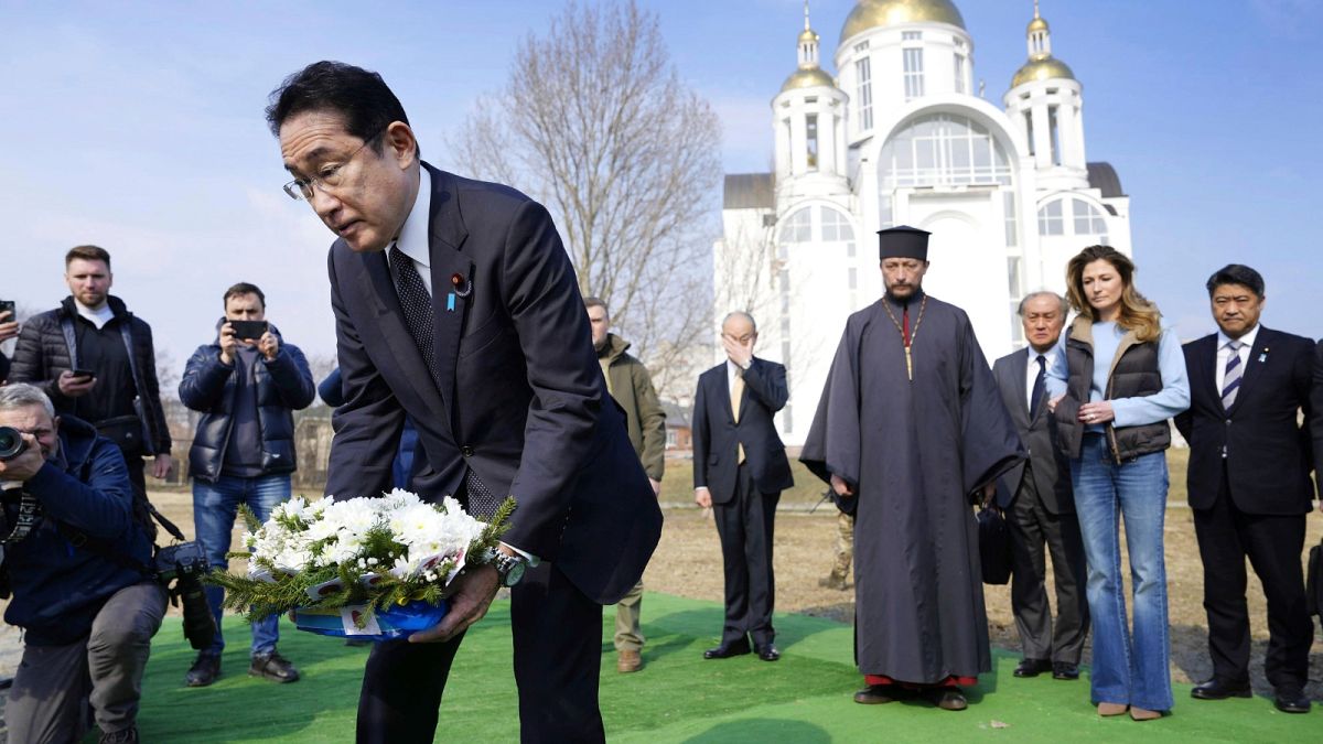 Japanese Prime Minister Fumio Kishida, front, lays the flowers at a church in Bucha, a town outside Kyiv, 21 March 2023