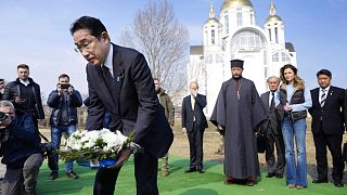 Japanese Prime Minister Fumio Kishida, front, lays the flowers at a church in Bucha, a town outside Kyiv, 21 March 2023