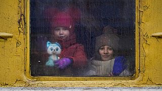 Children look out the window of an unheated Lviv-bound train, in Kyiv, Ukraine, Thursday, March 3, 2022.