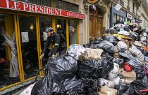 A cyclist rides past an uncollected garbage pile next to the cafe "The President" in Paris, Tuesday, March 21, 2023.