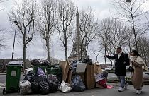 People walk past a pile of garbage near the Eiffel Tower in Paris, March 12, 2023, as strikes continue with uncollected garbage piling higher by the day. 