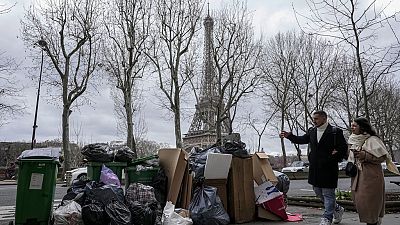 People walk past a pile of garbage near the Eiffel Tower in Paris, March 12, 2023, as strikes continue with uncollected garbage piling higher by the day. 