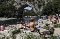 People relax on a beach next to "Le Pont d'Arc" rock on the Ardeche river in the Gorges de l'Ardeche.