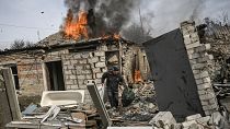 A man tries to save the belongings from a neighbour's burning house in Chasiv Yar, eastern Ukraine 21 March 2023