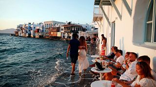 People sit at a bar in Little Venice on the Aegean Sea island of Mykonos, Greece, Sunday, Aug. 16, 2020.