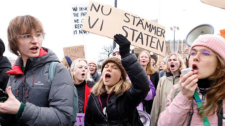 Climate activist Greta Thunberg holds a sign reading "Now we sue the State" at a protest in Stockholm on 25 November 2022.