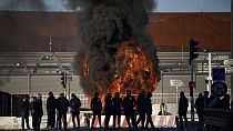 Dock workers stand in front of a burning barricade next the port of Marseille southern France, Wednesday, March 22, 2023.