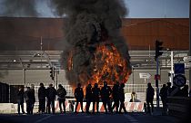 Dock workers stand in front of a burning barricade next the port of Marseille southern France, Wednesday, March 22, 2023.