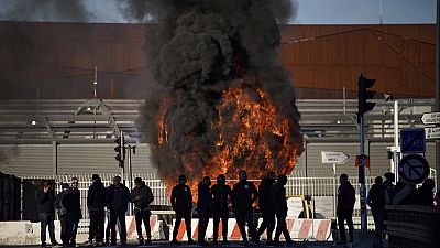 Dock workers stand in front of a burning barricade next the port of Marseille southern France, Wednesday, March 22, 2023.