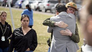 Un estudiante, a la derecha, abraza a un padre en una manifestación después del  tiroteo en East High School, el miércoles, 22 de marzo de 2023, en Denver.