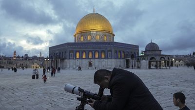 A man observes the moon through a telescope next to the Dome of Rock Mosque at the Al-Aqsa Mosque compound in Jerusalem's Old City, Tuesday, March 21, 2023