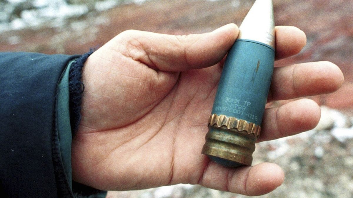 FILE - A member of a radiation team holds a 30mm armour-piercing shell containing depleted uranium, used by NATO during air strikes on Bosnia in 1995.