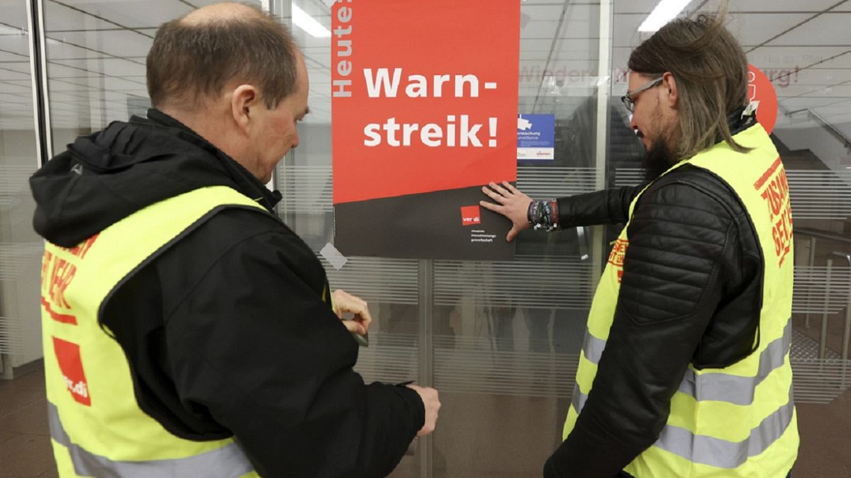 Union representatives stick a poster reading "Warning strike!" on a glass door at Hamburg Airport .