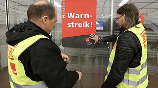 Union representatives stick a poster reading "Warning strike!" on a glass door at Hamburg Airport .