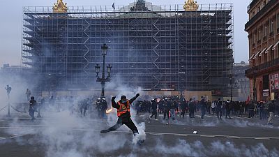 Manifestantes corren entre los gases lacrimógenos durante una manifestación en Lyon, en el centro de Francia, el jueves 23 de marzo de 2023. 