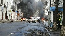 Cars burn and smoke raises after a deadly Russian rocket attack hit the city center in Kherson, Ukraine, Saturday, Dec. 24, 2022