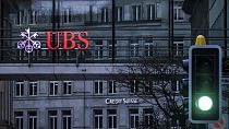 Un semáforo se pone en verde delante de los letreros de los bancos suizos Credit Suisse y UBS, en Zúrich, Suiza, el domingo 19 de marzo de 2023.