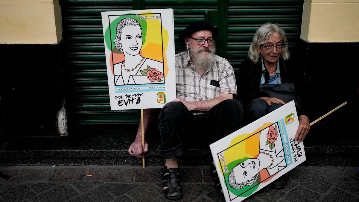 People hold signs with the image of Argentina's former first lady María Eva Duarte de Perón, as they rest during a march marking the 47th anniversary of the military coup. 