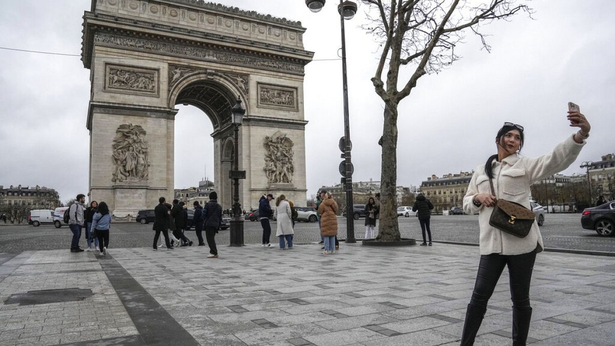  سائحة تلتقط صورة سيلفي بهاتفها المحمول في شارع الشانزليزيه مع قوس النصر، باريس، باريس، 12 يناير، 2023