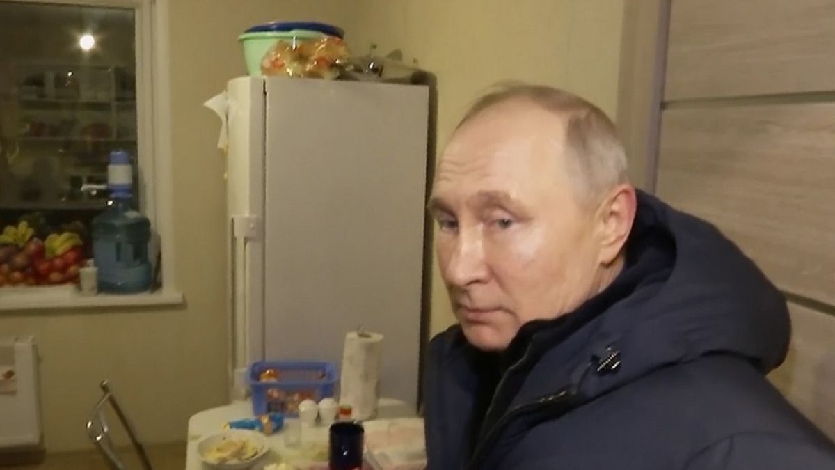 Le président russe Vladimir Poutine écoute les habitants de leur nouvel appartement lors de sa visite à Marioupol le dimanche 19 mars 2023