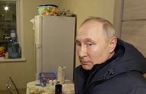 Le président russe Vladimir Poutine écoute les habitants de leur nouvel appartement lors de sa visite à Marioupol le dimanche 19 mars 2023