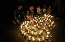 Personas usan velas para crear el número 60, que representa los minutos en una hora, mientras marcan la Hora del Planeta en La Paz, Bolivia, el sábado 25 de marzo de 2023.