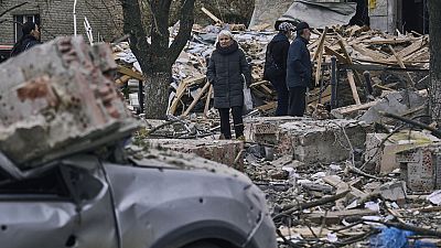 People stand in front of a heavily damaged building after an attack in Sloviansk