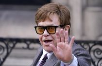 El músico Elton John saluda a los periodistas a su salida del Tribunal Superior de Londres el lunes 27 de marzo