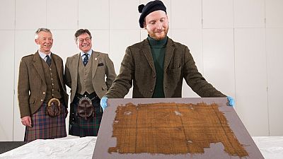 V&A Dundee curator James Wylie with the Glen Affric tartan, with STA's Peter MacDonald and John McLeish looking on