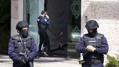 Police officers stand at the entrance of an Ismaili Muslim center in Lisbon, Portugal, Tuesday, March 28, 2023.