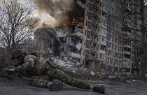 Ukrán rendőrtiszt fedezéket keres egy égő ház előtt Avdijivkában